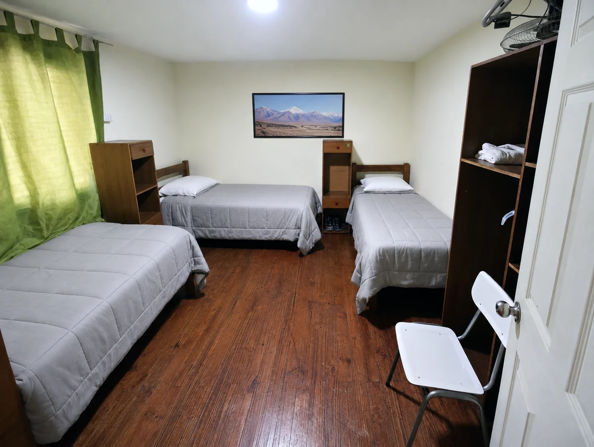 Habitación compartida de Residencial El Aromo en Rancagua, con tres camas individuales y piso de madera