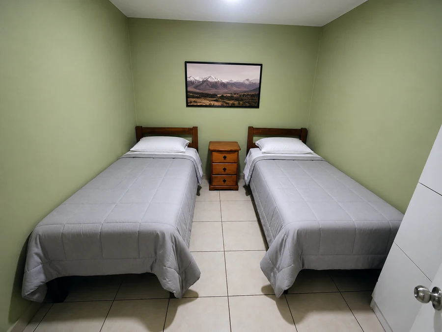 Habitación doble equipada en Residencial El Aromo, con velador y camas perfectamente hechas